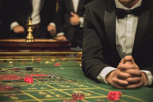 A professional dealer in a tuxedo greeting players at the roulette table, symbolizing the authentic live casino feel at 10WIN.