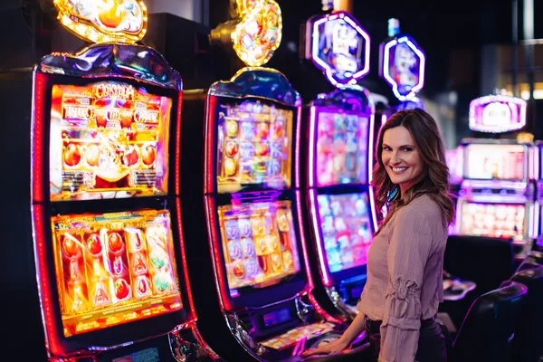 A woman smiling by bright slot machines showing lucky symbols, showcasing the exciting slot offerings at 10WIN.