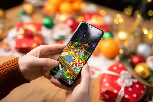 A player using their smartphone during a festive local event, representing 10WIN’s fully mobile-friendly casino.